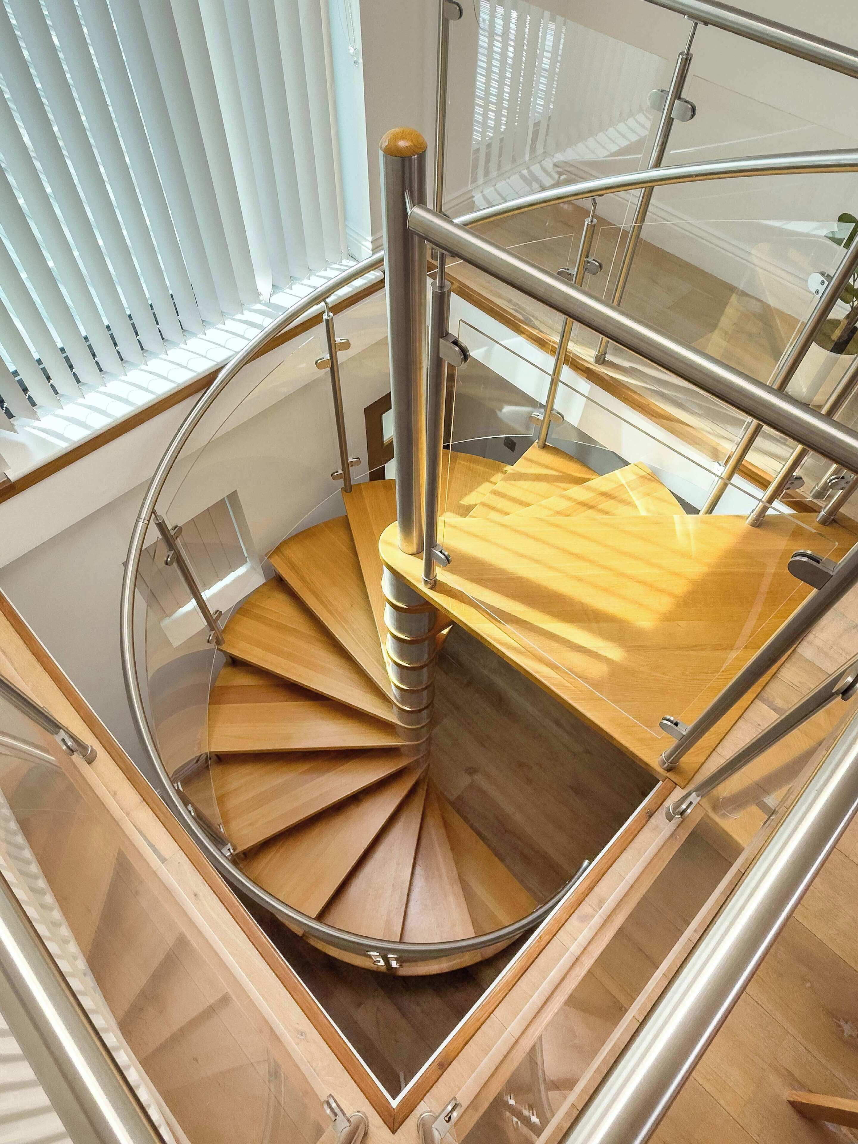 A spiral staircase with a glass railing and wooden steps.