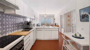 Una cocina moderna con armarios blancos, salpicadero de azulejos azules y una isla central.
