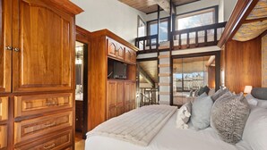 A bedroom with a large bed, wooden wardrobe, and a staircase leading to an upper level. - 3BR Penthouse, Hot Tub, Mtn Views! Hiking Trails! (Snowmass Village)