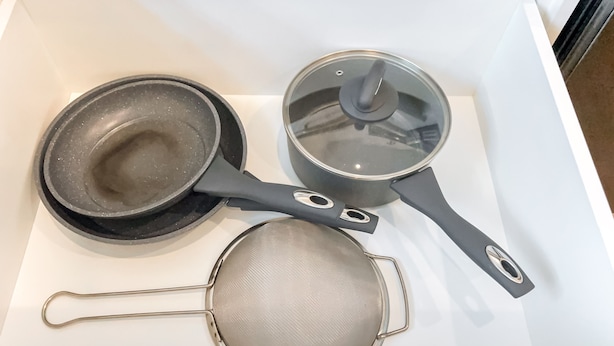 A kitchen with a white countertop, a frying pan, a saucepan, and a strainer. - FreshModernCozyQuietRetreat | WEM | Garage | KingBed (Edmonton)