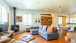 A spacious living room with a fireplace, a sofa, a dining table, and a kitchen area. - Artist's farm house children loft m/s Redmond, Seattle (Duvall)