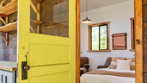 A yellow door leading to a bedroom with a bed, a chair, and a window. - Artist's farm house children loft m/s Redmond, Seattle (Duvall)