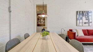A modern dining area with a wooden table, a potted plant, and a red sofa.
