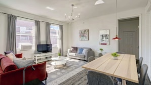 A modern living room with a sofa, TV, and dining table.