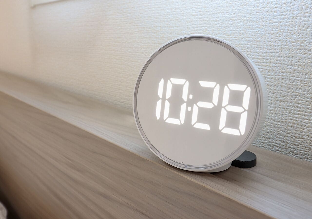 Eine runde digitale Uhr mit weißer Anzeige auf einer Holzoberfläche.