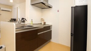 Una cucina con pensili in legno scuro, una cappa in acciaio inossidabile, un frigorifero nero e un lavello con rubinetto.