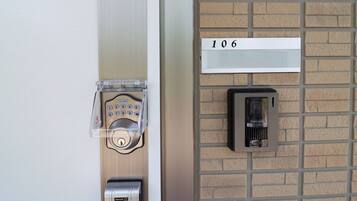 Una puerta con teclado electrónico, lector de tarjetas y letrero con el número de habitación.