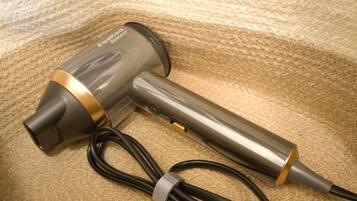 A hair dryer with a cord and a power adapter on a textured surface.
