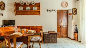 A dining area with a wooden table and chairs, a television, and a shelf with decorative plates. - Lovely apartment for 3 people with TV and balcony (Nesso)