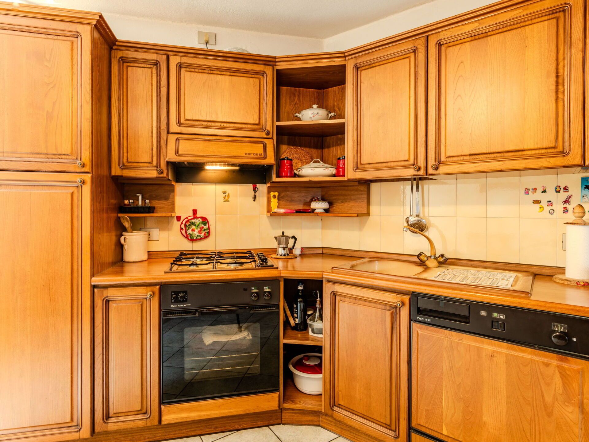 A kitchen with wooden cabinets, a gas stove, an oven, a dishwasher, and a sink.