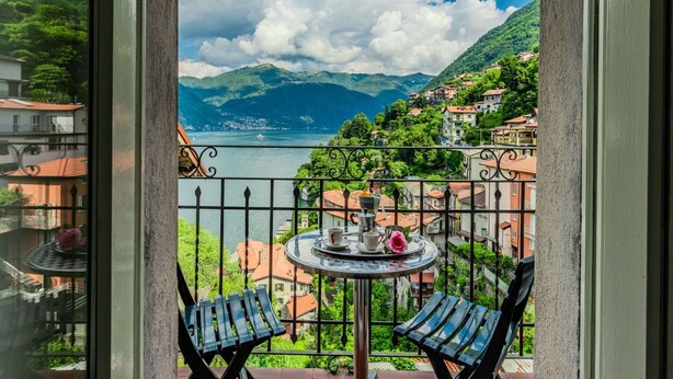 A balcony with a table and chairs, overlooking a lake and mountains. - Lovely apartment for 3 people with TV and balcony (Nesso)