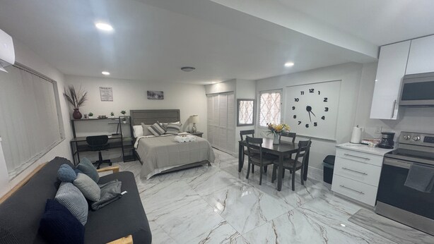 Un dormitorio moderno con cama, mesita de noche y un escritorio con silla.