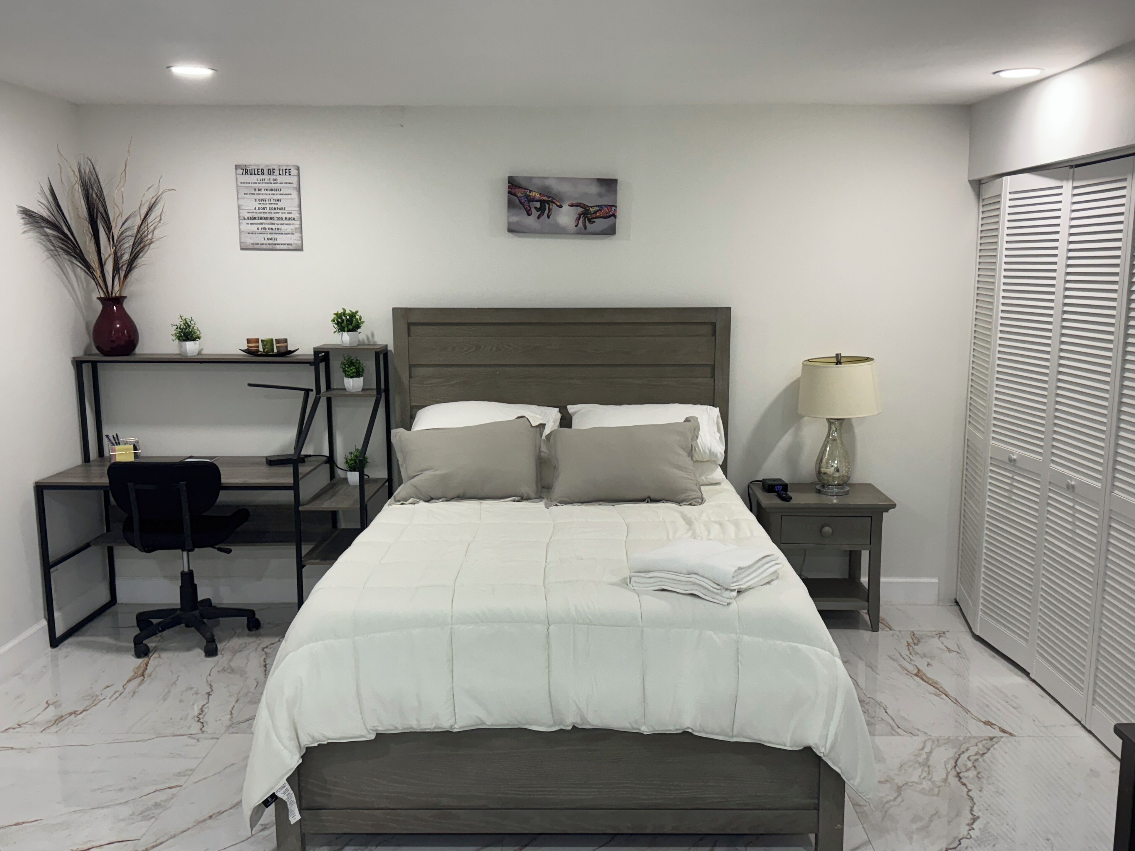 A neatly arranged bedroom with a bed, bedside tables, a desk, and a chair.