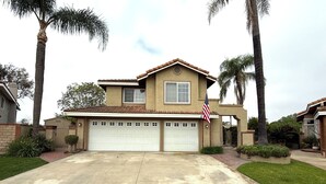 A two-story house with a garage, a small porch, and a well-maintained lawn. - Mountain View • Pool House • BBQ (Chino Hills)