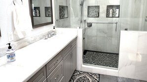 A modern bathroom with a glass-enclosed shower, a large mirror, and a marble countertop. - Mountain View • Pool House • BBQ (Chino Hills)