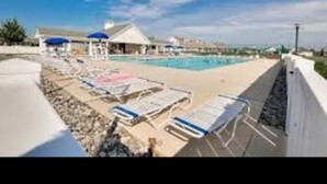 Un hôtel situé en bord de mer, doté d’une piscine, de chaises longues et de parasols.