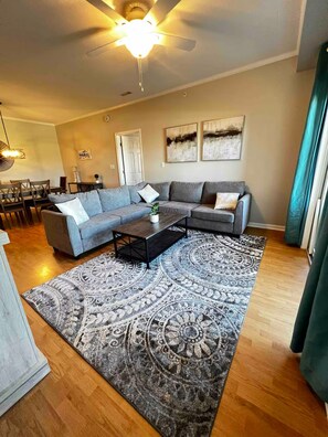 A living room with a sectional sofa, a coffee table, a patterned rug, and a ceiling fan. - Cozy condo in Villages of Five Points, Lewes (Lewes)