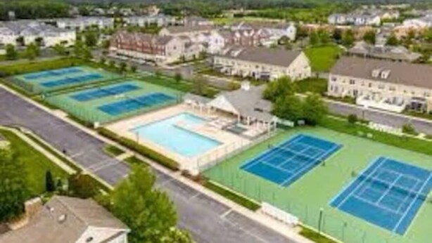 Un quartier résidentiel doté de plusieurs courts de tennis et d’un grand bâtiment à toit en pente.
