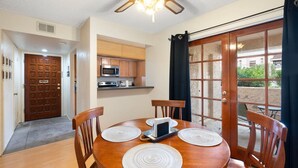 A dining area with a wooden table, four chairs, and a ceiling fan.