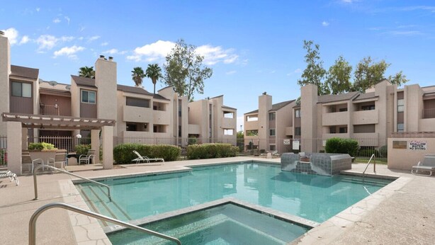 A swimming pool surrounded by apartment buildings with a sign indicating shallow water and no diving.
