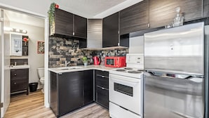 Une cuisine moderne avec des meubles de couleur sombre, un réfrigérateur en acier inoxydable, un four à micro-ondes et une cuisinière.