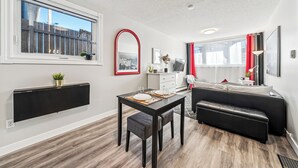 Un salon moderne comprenant un coin repas, un canapé noir, un téléviseur et une fenêtre donnant sur un beau paysage.