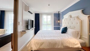 A bedroom with a large bed, a television, and a desk.