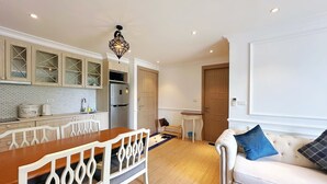 A modern kitchen with white cabinets, a wooden dining table, and a built-in oven.