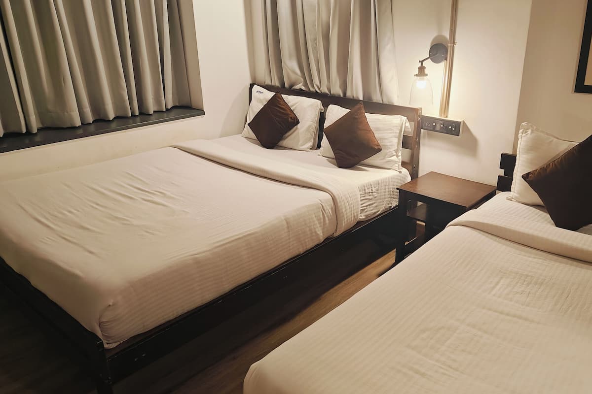 Ein Hotelzimmer mit zwei Betten, einem Nachttisch, einer Lampe und einem gerahmten Bild an der Wand.