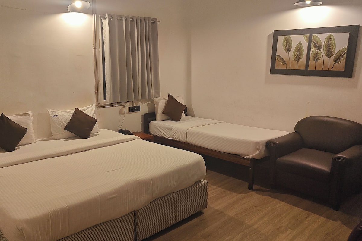 Ein Hotelzimmer mit zwei Einzelbetten, einem Sessel, einem Nachttisch und einem Wandbild.