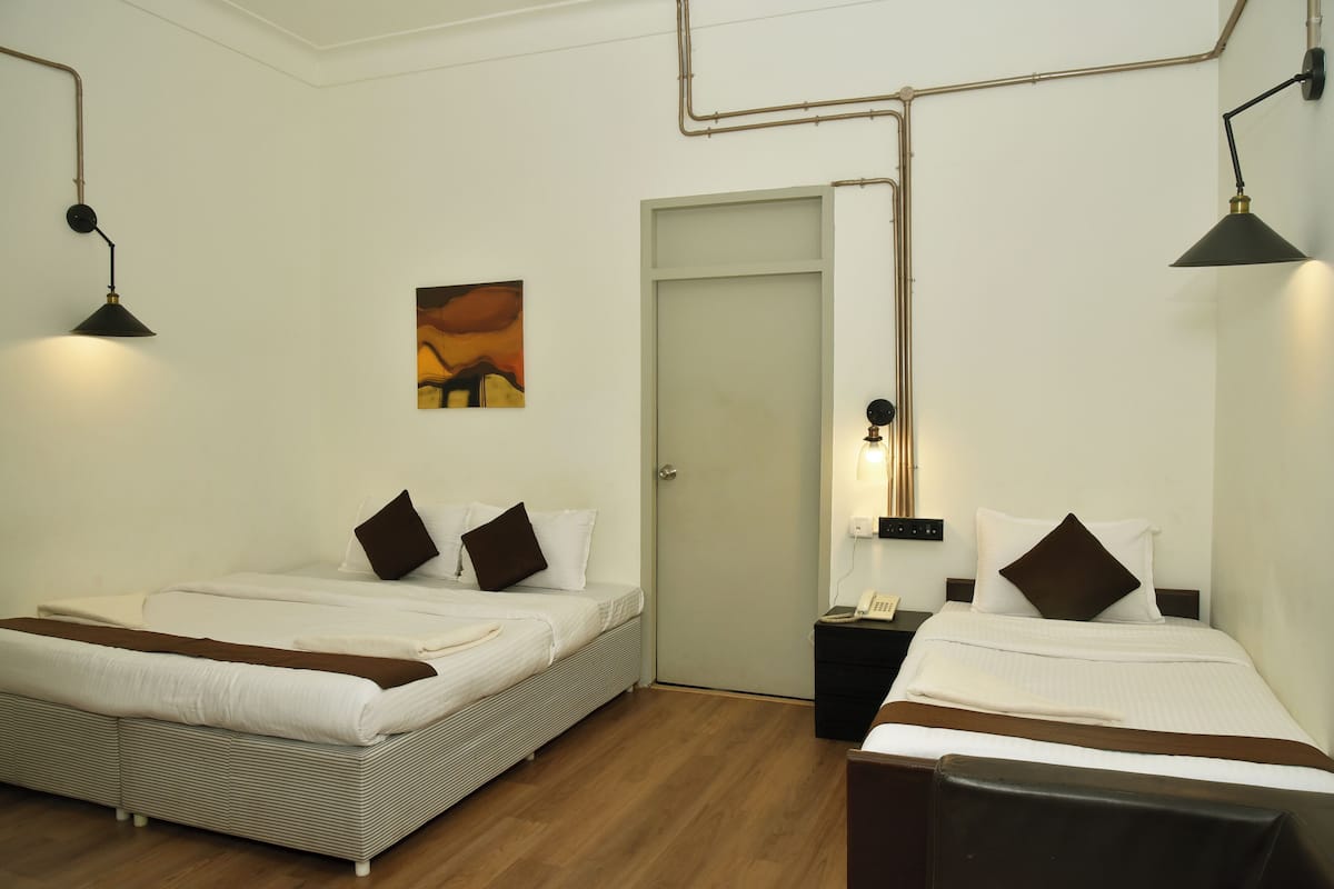 Ein Hotelzimmer mit zwei Betten, Holzboden, einer Tür und einem Bild an der Wand.