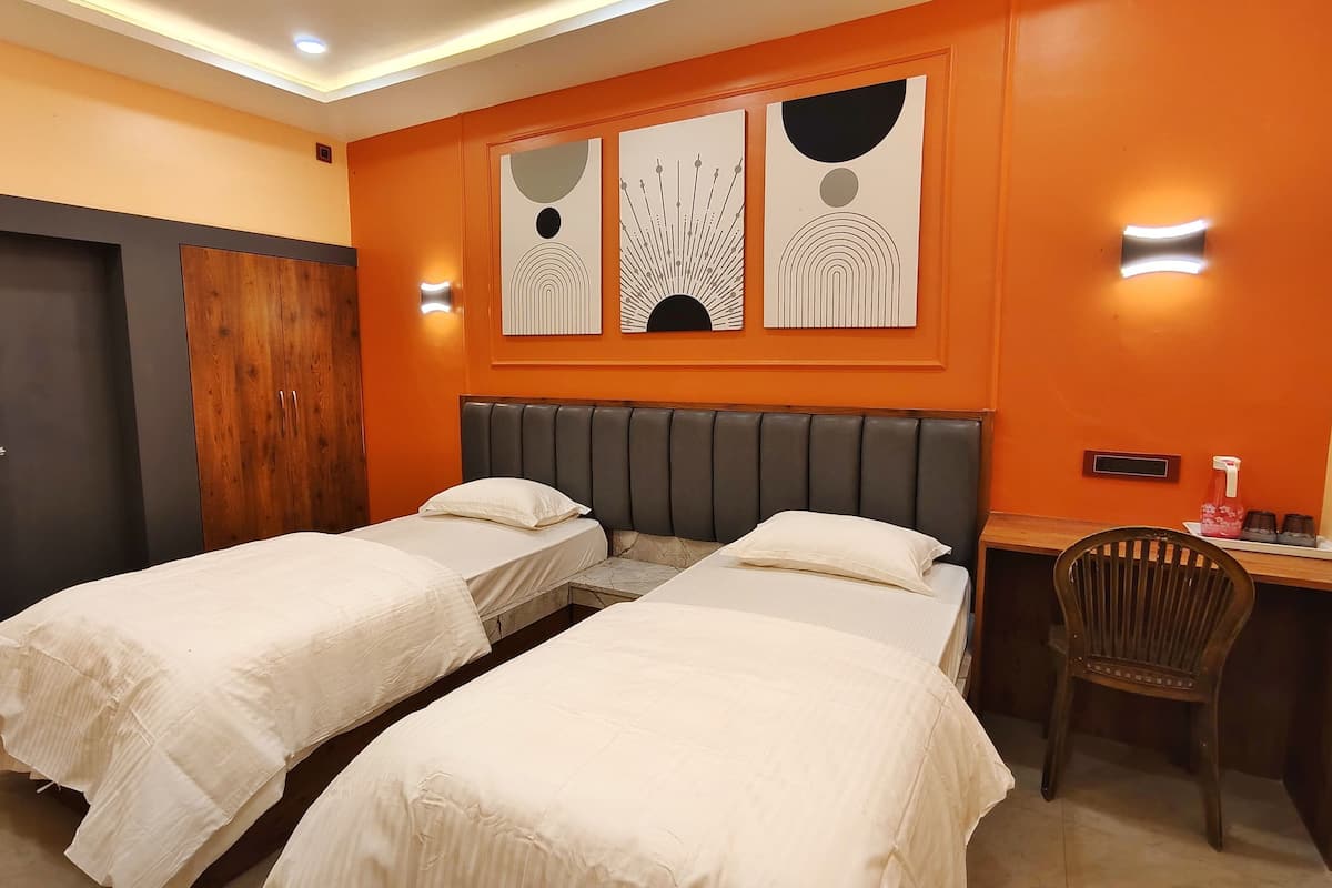 A hotel room with two beds, a desk, and a chair.