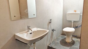 A bathroom with a sink, mirror, toilet, and visible plumbing. - The Saanjh Hotel (Angul)