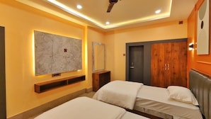 A hotel room with two beds, a wooden wardrobe, a marble artwork on the wall, and a ceiling fan. - The Saanjh Hotel (Angul)