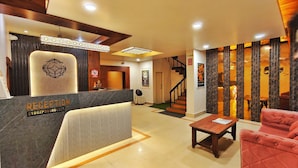 A reception area with a marble counter, a sign reading "RECEPTION," a staircase, and a wall with vertical wooden panels. - The Saanjh Hotel (Angul)
