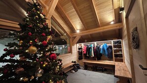 A wooden interior with a Christmas tree, a shoe rack, and a bench.