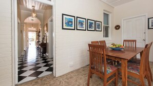 Ein Essbereich mit Schachbrettmuster-Boden, einem Holztisch mit Stühlen und gerahmten Kunstwerken an der Wand.