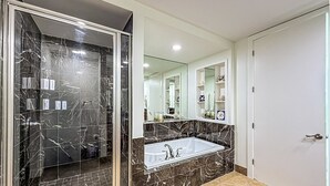 Ein modernes Badezimmer mit einer gläsernen Duschkabine, einer großzügigen Badewanne und einem Waschtisch mit Spiegel.