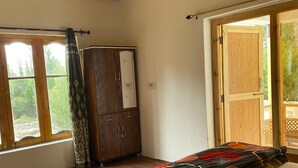 Un dormitorio con una cama grande, vigas de madera en el techo, un armario y una ventana con vistas a zonas verdes.