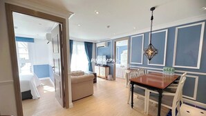 A hotel room with a dining area, a sofa, and a bed. - E8 - 2bedroom french style beautiful pool view Pattaya Seven seas cote d azur (Tambon Na Chom Thian)