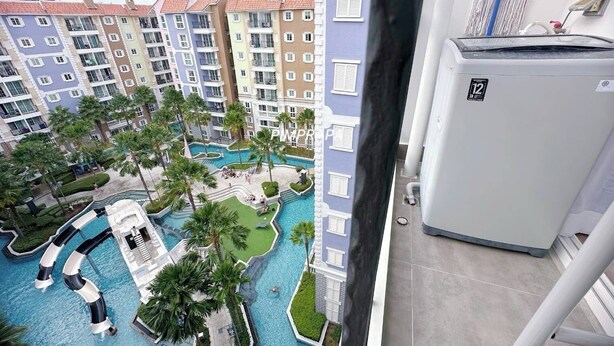 A high-rise hotel with a swimming pool area, including a water slide and palm trees. - E8 - 2bedroom french style beautiful pool view Pattaya Seven seas cote d azur (Tambon Na Chom Thian)
