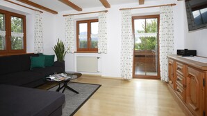 A living room with a sofa, coffee table, and a view of a balcony. - Apartment no. 3 with mountain view, 62m², modern furnishings and very large south/east-facing balcony (Übersee)