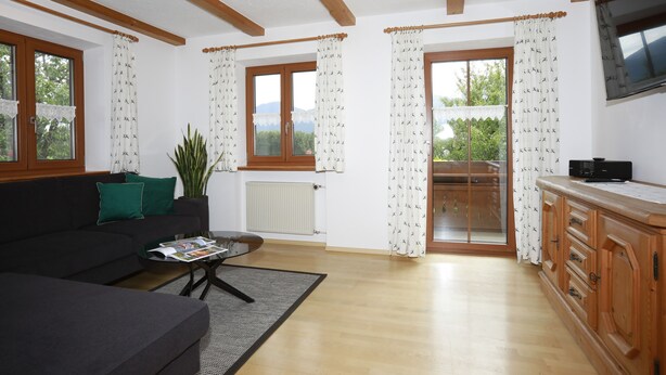 A living room with a sofa, coffee table, and a view of a balcony. - Apartment no. 3 with mountain view, 62m², modern furnishings and very large south/east-facing balcony (Übersee)