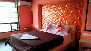 A modern hotel room with a geometric patterned headboard, a neatly made bed with striped pillows, and a small round table. - Eco House Boats - Alleppey Kerala (Alappuzha)