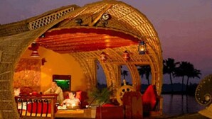 A boat with a woven structure, a steering wheel, and a person seated at a table. - Eco House Boats - Alleppey Kerala (Alappuzha)