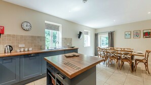 A modern kitchen with grey cabinets, a wooden island, and a dining area with wooden chairs.