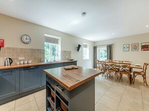 Une cuisine moderne avec des meubles gris, un îlot central en bois et un coin repas avec des chaises en bois.