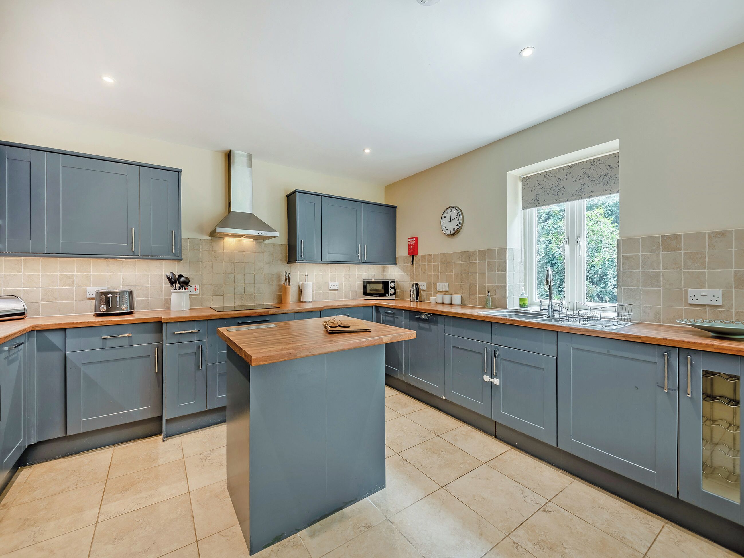 A modern kitchen with grey cabinets, a central island, a microwave, and a window with a view.