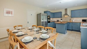 A modern kitchen with blue cabinets, a central island, and a dining area with wooden chairs and a table set for six.