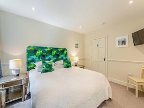 Een hotelkamer met een bed, nachtkastjes, een stoel, een deur en een tv aan de muur.